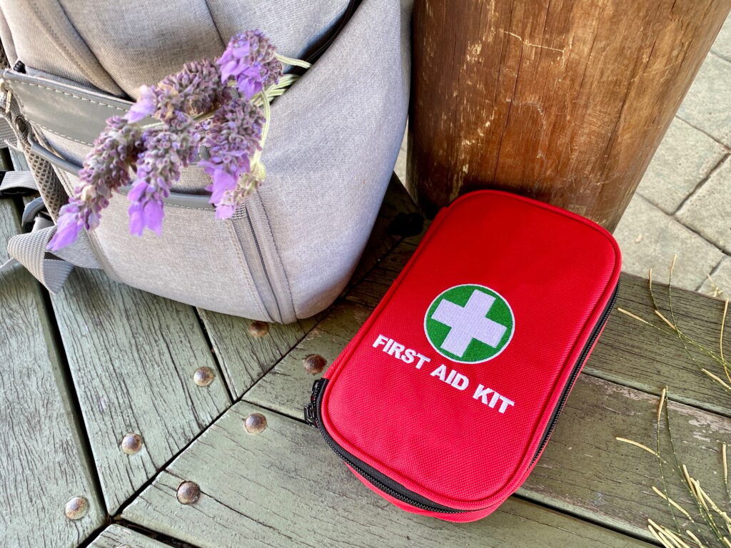 First aid kit and backpack with lavender on the bench in park