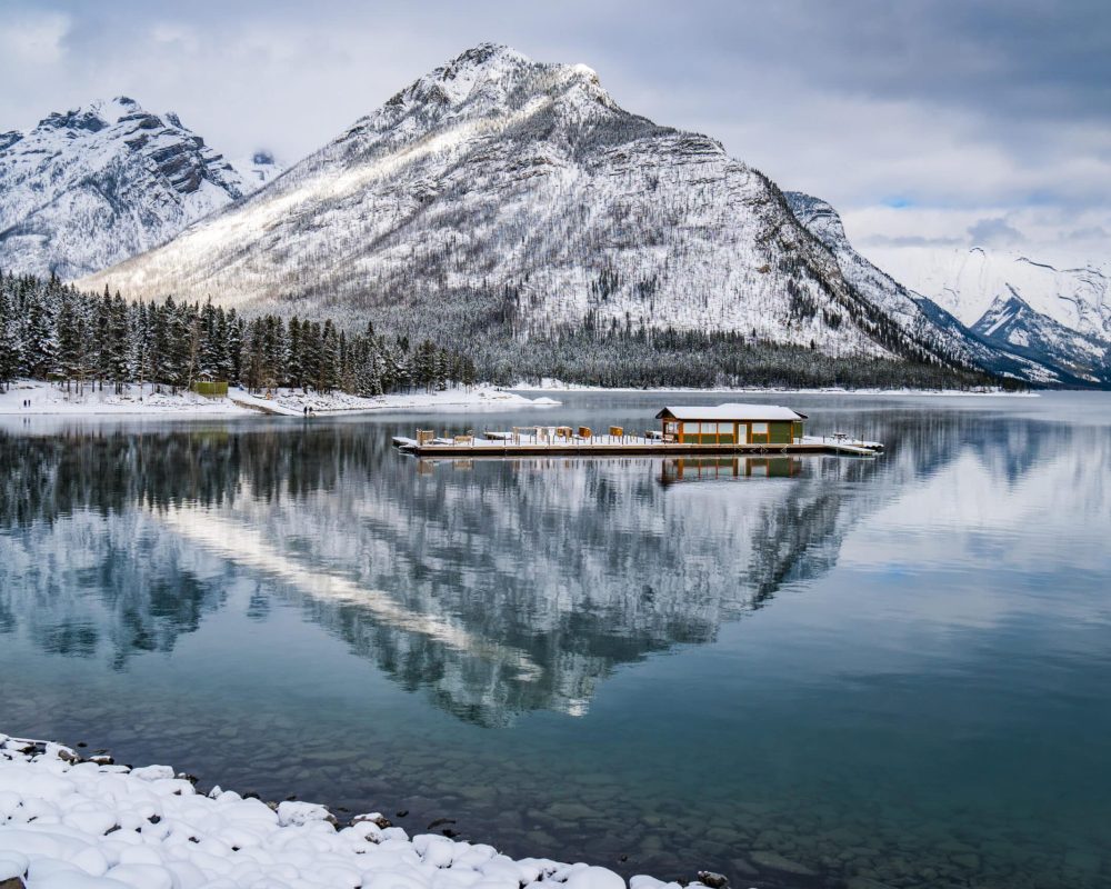 Clear,Water,Of,Lake,Minnewanka,,Surrounding,Forest,And,Mountains,Covered